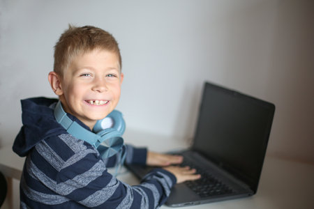 Portrait of a boy with laptop and headset at home or officeの写真素材
