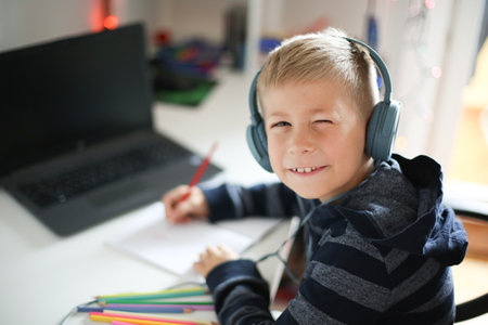 Portrait of a boy with laptop and headset at home or officeの写真素材