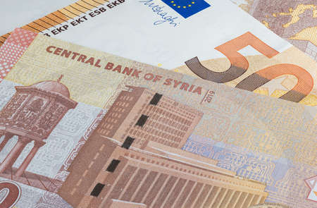 Syrian pound or Lira together with Euro banknotes. Money of the Arabic country. Close up detailed money background wallpaper. Banknotes of the battered by the war country of Syria. Currency banknotesの写真素材