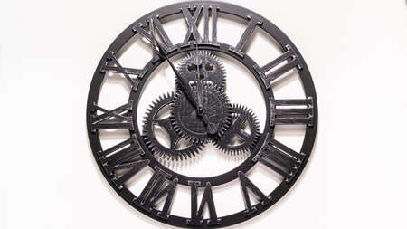 Black metal wall clock. Shadows over the clock face. Gears in the middle of the clock. Old antique...