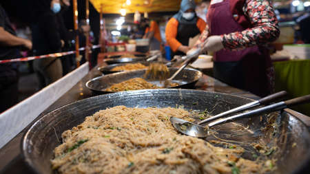 Street food night market at  Putrajaya, near Kuala Lumpur. A fried noodles store in the fresh market Putrajaya. Barrier tape next to it ensures social distanceのeditorial素材