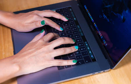 Cyberjaya, Malaysia - October 13, 2020:  Woman hands typing on a computer keyboard. Female hands writing on a laptop keyboard. Fingernails are painted in green. Home office during the lockdownのeditorial素材