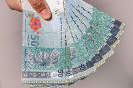 A collection of Fifty malaysian ringgit banknotes in a female hand. Woman hand show Malaysia Ringgit...