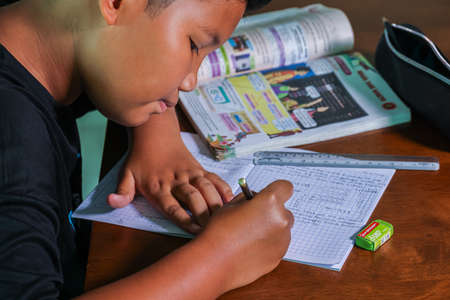 Cyberjaya, Selangor, Malaysia - September 23, 2020: Home schooling in Malaysia. Due to the corona crisis, young boy do school task at home. Teenager student works on mathematic task, home schoolingのeditorial素材