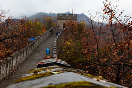 The great Wall of China in Autumn, in the mountains near Beijing. A rainy day where the rain clouds creep over the mountain peaks. The colorful autumn forest in the background. Close up to the wallのeditorial素材