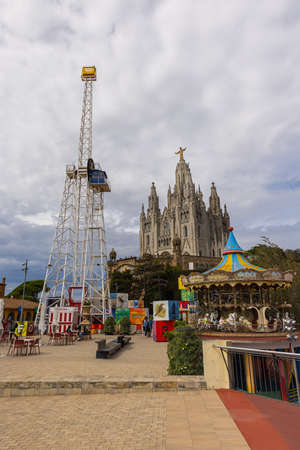 Barcelona, Spain - September 22, 2021: The Temple of the Sacred Heart of Jesus at the peak of the Parc Tibidabo. Cathedral church with golden Jesus. Amusement park from in the foreground of the churchのeditorial素材