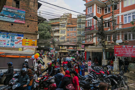 Kathmandu, Nepal - October 30, 2021: Busy street in the capital city of Nepal. Motorcycles and cars share the limited space on the road. Electrical cable crossing overhead the street. dusty streetのeditorial素材