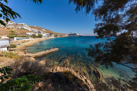 Mykonos, Greece - August 1, 2021: Panoramic wide angle view over the beach side of the island Mykonos. Mykonos is located in the cyclades archipelago in the Aegean Sea. Turquoise water on sand beach.のeditorial素材