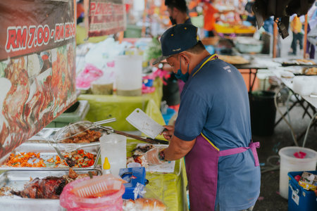 Kuala Lumpur, Malaysia - June 21, 2022: Man preparing Nasi Ayam or english chicken rice for selling on a street food market. Traditional Malaysian chicken rice is the most famous dish on the marketのeditorial素材