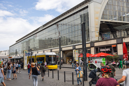 Berlin, Germany - June 29, 2022: Berlin Friedrichstrasse train station with a tram waiting on the tram stop. Busy place in East Berlin. People are waiting for the tram. A taxi car passing byのeditorial素材