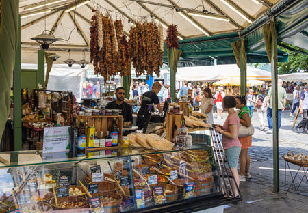 Munich, Germany - July 6, 2022: Sevdas stall at the Viktualienmarkt sells mediterranean delicacies. Flatbread, olives and various salads are available in the display. Customers stand at the counterのeditorial素材