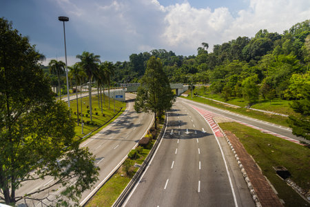 Unusual empty highway in the malaysia capital Kuala Lumpur near Jalan Parlimen. Where normally car follows car and daily traffic jams the air polluted, only hot asphalt remains. No cars on the streetのeditorial素材