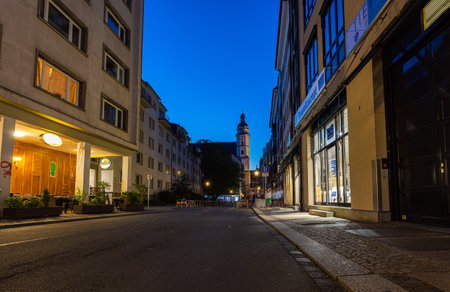 Leipzig, Germany - July 02, 2022: St. Thomas Church or Thomaskirche, view along Burgstrasse on a summer night dawn. Buildings illuminated by old lantern or street lamps. No people on the streetのeditorial素材