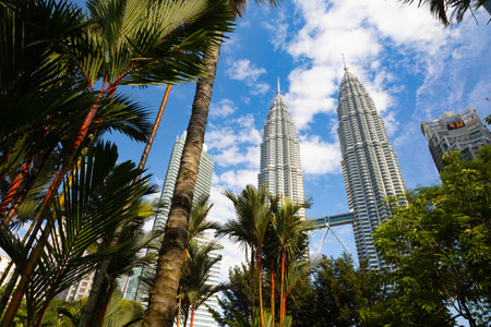 Kuala Lumpur, Malaysia - August 13, 2022: View of the Twin Towers through the palm trees of KLCC...