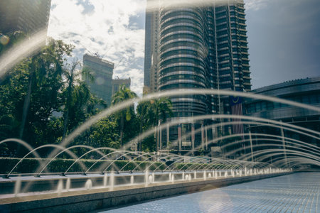 Kuala Lumpur, Malaysia - August 13, 2022: The KLCC Park with the water fountain show in front of the Petronas towers. Long exposure with silky water jet. City oasis around the twin towers Suria KLCCのeditorial素材