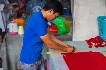 Ho Chi Minh City, Vietnam - November 8, 2022: Inside a small tailor shop in Saigon. A man mark the fabric to make a traditional ao dai dress, the traditional Vietnamese national dress. Local tailor storeのeditorial素材