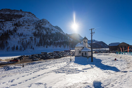 Falcade, Italy - February 14, 2023: Church in the mountain village of Falcade, Parish Church in the valley, winter scene with snowy roofs. Embedded between the high mountains of the Dolomitesのeditorial素材