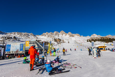 Falcade, Italy - February 15, 2023: At the foot of the mountains. Skiers get ready for the ski run. A ski lift takes skiers to the peak of the mountain. Group of people recovering from downhill skiingのeditorial素材