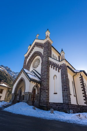 Falcade, Italy - February 14, 2023: Church in the mountain village of Falcade, Parish Church in the valley, winter scene with snowy roofs. Embedded between the high mountains of the Dolomitesのeditorial素材