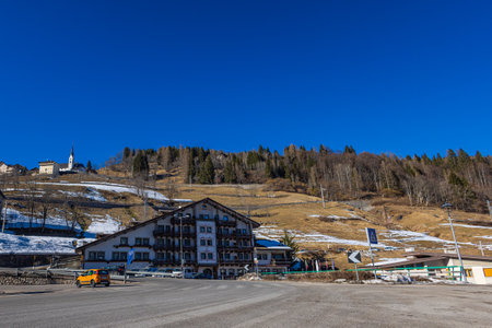 Falcade, Italy - February 14, 2023: Church in the mountain village of Falcade, Parish Church in the valley, winter scene with snowy roofs. Embedded between the high mountains of the Dolomitesのeditorial素材