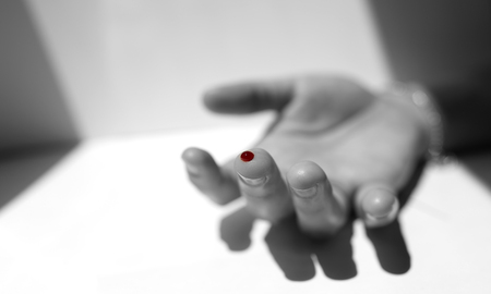 A black and white finger with red blood dropの写真素材