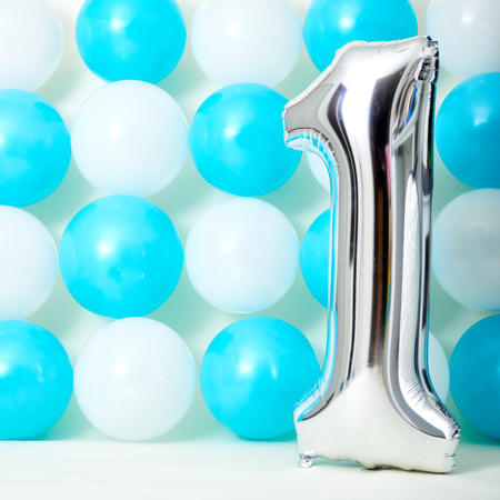 Shiny first birthday balloon with blue and white balloons background.の写真素材