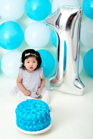 Asian baby girls first blue birthday cake smashing with balloons decoration.の写真素材