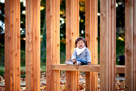 Baby girl sitting on the wood bench in the parkの写真素材