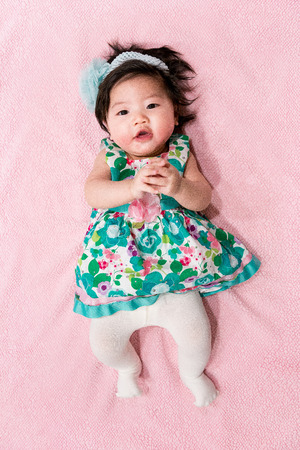 baby girl with cute floral dress and pink backgroundの写真素材
