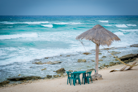 Table set on beach with grass umbrella shadeの写真素材