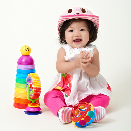 Asian baby girl wearing colorful outfit playing with toys.の写真素材