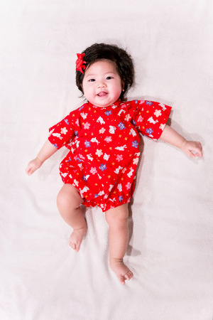 baby girl with cute red Japanese style outfit and white backgroundの写真素材