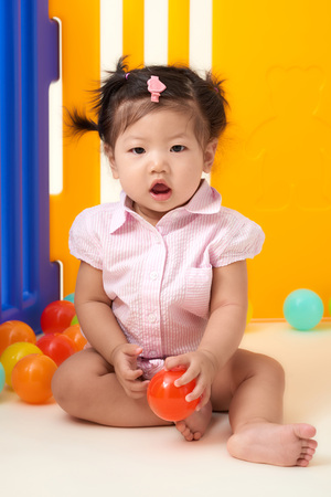 Asian Chinese baby girl playing with colorful balls fenced.の写真素材