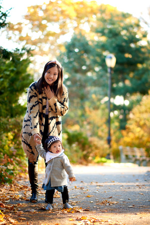 Mother holding daughter in stunning fall scene in the parkの写真素材