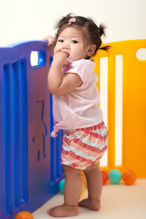 Asian Chinese baby girl playing with colorful balls fenced.の写真素材