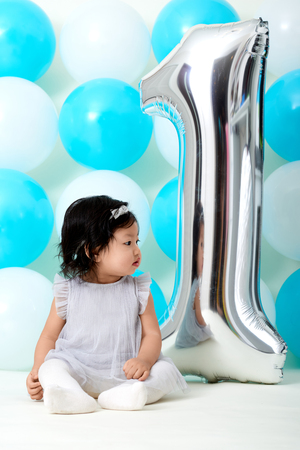Asian baby girls first birthday with shiny and blue ballonsの写真素材