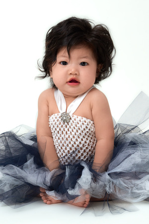 Cute Asian baby girl in flare dress sitting up.の写真素材