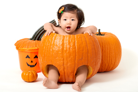 Baby girl sitting inside the pumpkin for Halloweenの写真素材