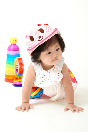 Asian baby girl wearing colorful outfit playing with toys.の写真素材