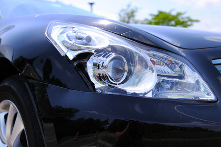 Headlight and body of a black car damaged in collisionの写真素材