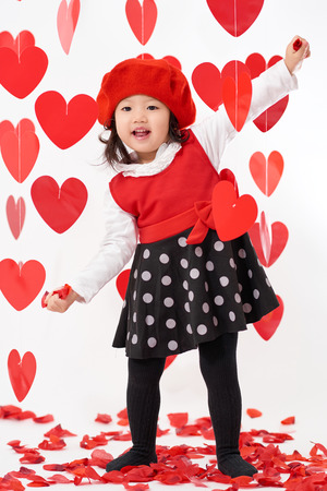 Cute Asian baby girl with hearts and rose pedals on Valentine's Dayの写真素材