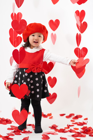 Cute Asian baby girl with hearts and rose pedals on Valentine's Dayの写真素材