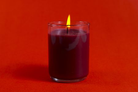 A small Christmas candle shot against a red background.の写真素材