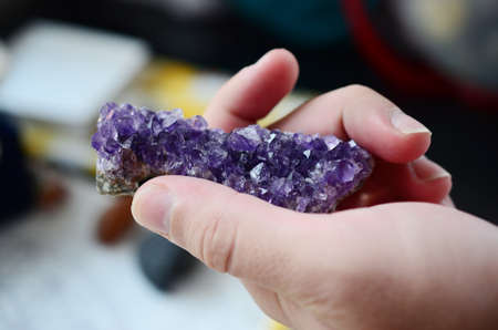 Amethyst crystal cluster being held in woman's hand, lush purple healing crystal cluster. Macro...