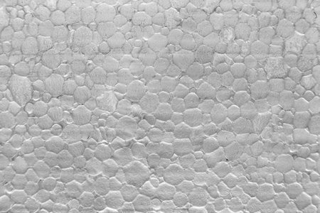 Horizontal macro shot (detail plan) of polystyrene foam. Cellular texture, white gray background. Sharp focus filling the frame, ideal for packaging or insulation backgroundsの写真素材
