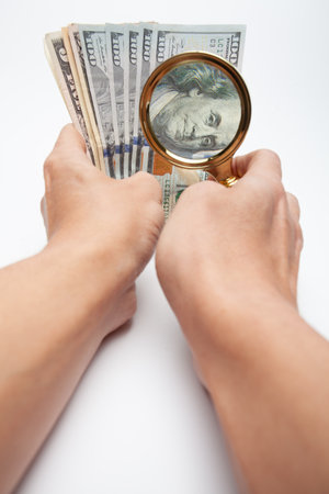 Vertical photo of hands inspecting money. Ideal for illustrating audit, finance, wealth, investment analysis, and economic growth conceptsの写真素材