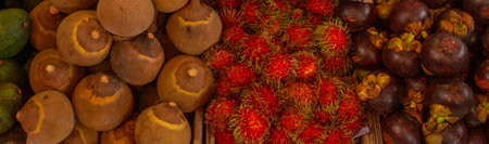 Horizontal full-frame shot of mangosteen, rambutan and sapote at a Colombian market. Dense, colorful...