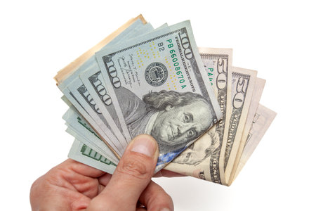 Closeup of hand fanning $100 and $50 USD bills on a white background. Ideal for illustrating...