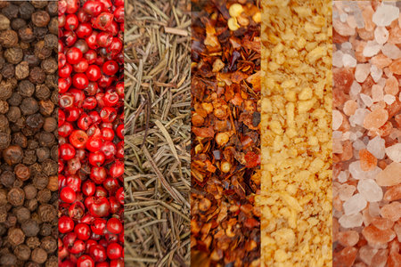 Macro top view of assorted spices scattered on a white background, including black pepper, pink...