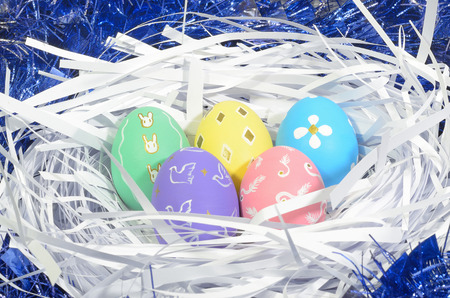 ester eggs on white paper hay and blue background